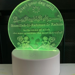 May include: A green acrylic night light with a white base. The light features a floral design and the text "Start your day with Bismillah-Ir-Rahman-Ir Rahim In the name of Allah the most gracious, the most merciful".