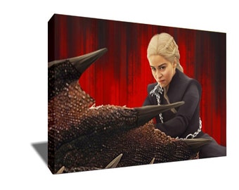May include: A woman with blonde hair and a serious expression sits on a large, dark, scaly creature. She is wearing a black, long-sleeved shirt and a chain necklace. The background is a red curtain.