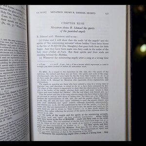 May include: An open book displaying text on the right-hand page, with the title "CHAPTER XLVII" and the subtitle "Metatron shows R. Ishmael the spirits of the punished angels." The left page also has text. The book is open.