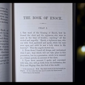 Może przedstawiać: Otwarta książka z tytułem "THE BOOK OF ENOCH." Strona wyświetla tekst czcionką szeryfową, z tytułem rozdziału "CHAP. I." i numerowanymi akapitami. Tekst jest czarnym tuszem na postarzanym, kremowym papierze.