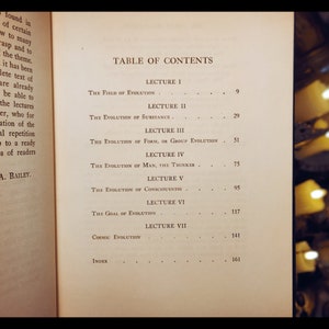 May include: A black and white book with the title "Table of Contents" and a list of chapters with page numbers. The chapters include "The Field of Evolution", "The Evolution of Substance", "The Evolution of Form, or Group Evolution", "The Evolution of Man, The Thinker", "The Evolution of Consciousness", "The Goal of Evolution", and "Cosmic Evolution".