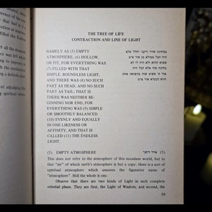 K&ouml;nnte beinhalten: Offene Buchseite mit dem Titel "The Tree of Life: Contraction and Line of Light" in Englisch und Hebr&auml;isch. Der Text ist auf einem leicht vergilbten Papier gedruckt, mit dunklem Hintergrund und verschwommenen Kerzen.