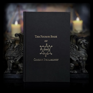 Könnte beinhalten: Ein schwarzes gebundenes Buch mit dem Titel The Fourth Book of Occult Philosophy mit goldener Prägeschrift und einem zentralen Hexagramm-Symbol. Das Buch steht zwischen zwei dunkelgrauen, steinartigen Greifenstatuen mit sichtbaren Flügeln.