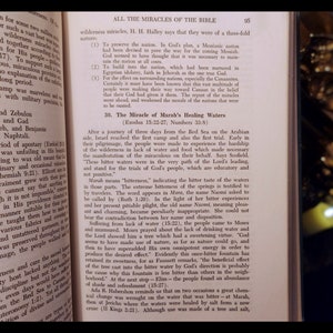 Może przedstawiać: Strona z książki o Biblii, z czarno-białym obrazkiem pustynnego krajobrazu i tekstem o Cudzie Uzdrawiających W&oacute;d Mary. Tekst opisuje podr&oacute;ż Izraelit&oacute;w przez pustynię i jak B&oacute;g zapewnił im wodę.