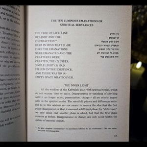 K&ouml;nnte beinhalten: Aufgeschlagenes Buch mit Text &uuml;ber Kabbala, mit hebr&auml;ischen Schriftzeichen und englischer &Uuml;bersetzung. Die Seite tr&auml;gt den Titel "Die zehn leuchtenden Emanationen oder spirituellen Substanzen". Kerzen im Hintergrund.