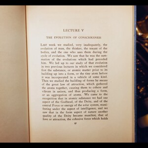 May include: A page from a vintage book with the title "Lecture V: The Evolution of Consciousness". The text discusses the evolution of man and the role of atoms in forming matter.