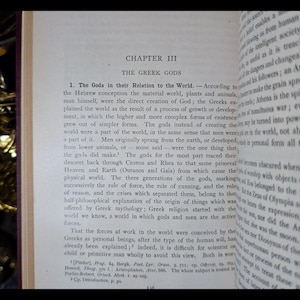 May include: A close-up of a page from a book titled "The Greek Gods". The text discusses the origin of the Greek gods and their relationship to the world. The text is in black and white.
