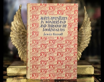 May include: A vintage copy of "Alice's Adventures in Wonderland and Through the Looking-Glass" by Lewis Carroll. The book has a red and white patterned cover and is propped up by golden wings.