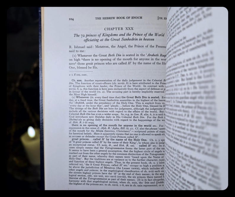 May include: An open book displaying text from "The Hebrew Book of Enoch." Chapter XXX is visible, discussing the 72 princes of Kingdoms. The text is in black font on off-white paper. The book is open, with the pages slightly curved.