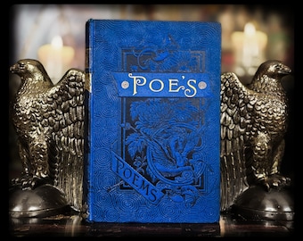 May include: A blue book titled "Poe's Poems" stands between two gold-colored eagle bookends. The book has ornate embossed designs and the title is in gold lettering. The bookends are detailed with feathers and stand on a dark surface.