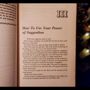 May include: A book titled "How To Use Your Power of Suggestion" with the Roman numeral III on the cover. The book is open to a page with text about the power of suggestion and how to use it to achieve your goals.