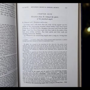 May include: An open book displaying text on the right-hand page, with the title "CHAPTER XLVII" and the subheading "Metatron shows R. Ishmael the spirits of the punished angels." The left page also has text. The book's pages are slightly yellowed.