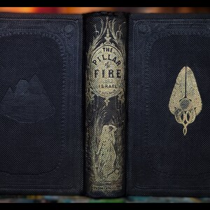 May include: A black leather-bound book with gold lettering on the spine. The title is "The Pillar of Fire" and the author is "J.H. Ingraham". The front and back covers have embossed designs.