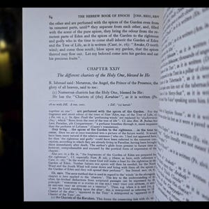 May include: An open book with text from "The Hebrew Book of Enoch" and Chapter XXIV. The pages are yellowed, with black text. Two lit candles are in the background, with a blurred focus.