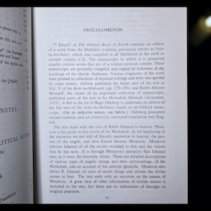 May include: An open book with the title "PROLEGOMENON" visible. The text discusses "3 Enoch" or The Hebrew Book of Enoch, with black text on a white page. The book is open to a page with text.