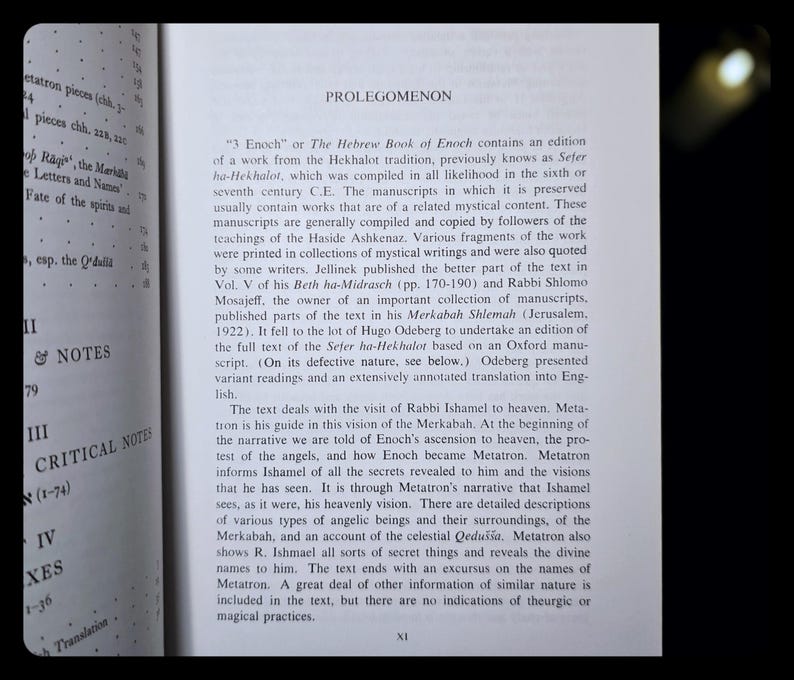 May include: An open book with the title "PROLEGOMENON" visible. The text discusses "3 Enoch" or The Hebrew Book of Enoch, with black text on a white page. The book is open to a page with text.