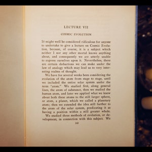 May include: A page from a book titled "Lecture VII: Cosmic Evolution". The text discusses the evolution of the atom from stage to stage, including the entire solar system. The text is printed in black ink on a white page.