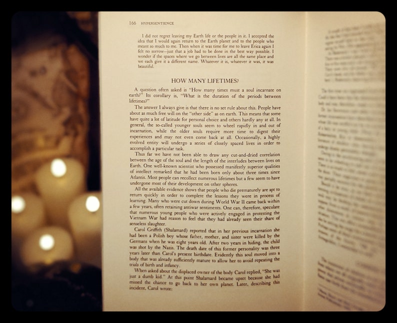 May include: Open book with a yellowed page, showing text about reincarnation and the duration of time between lives. The book is open to a page with the title "How Many Lifetimes?" and the text discusses the concept of souls returning to Earth after death. The book is illuminated by two candles, casting a warm glow on the page.