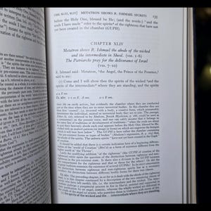 May include: An open book with text visible on the pages. The text includes the title "Metatron Shows R. Ishmael Secrets" and "Chapter XLIV". The pages are yellowed, and the book is open to a specific chapter.