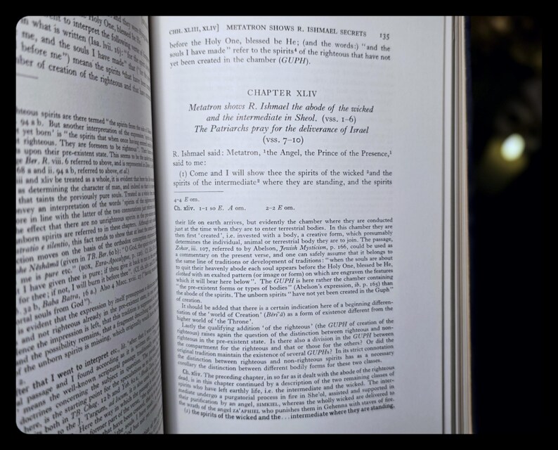 May include: An open book with text visible on the pages. The text includes the title "Metatron Shows R. Ishmael Secrets" and "Chapter XLIV". The pages are yellowed, and the book is open to a specific chapter.