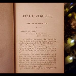 May include: A page from a book titled "The Pillar of Fire, or Israel in Bondage." The text describes the grandeur of ancient Egypt and its capital, Ox, the City of the Sun.