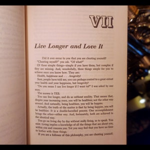 May include: A page from a book titled "Live Longer and Love It" with the text "Did it ever occur to you that you are cheating yourself?" and "The answer is YES." The text discusses the importance of health, happiness, and longevity.