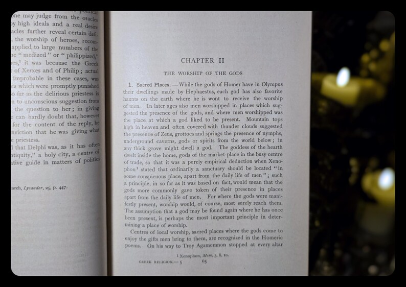 May include: A close-up of a page from a book titled "The Worship of the Gods." The text discusses the sacred places where the gods of Homer were worshipped in ancient Greece. The page is yellowed with age and has a worn, vintage look.