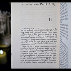 May include: Open book page with the title "Developing Latent Psychic Ability" and the number "11". The text discusses psychic abilities, their development, and different perspectives on the ultimate power. The page is set against a dark background.