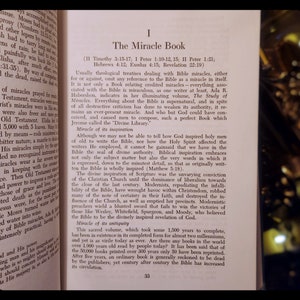 Może przedstawiać: Antyczna książka zatytułowana "The Miracle Book" z brązową sk&oacute;rzaną okładką i złotymi literami. Książka omawia inspirację i starożytność Biblii.