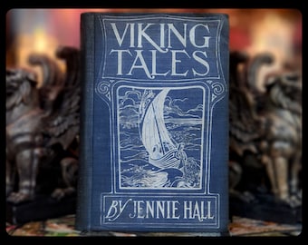 May include: A vintage book titled "Viking Tales" by Jennie Hall. The cover features a blue background with a white illustration of a ship sailing on the sea.