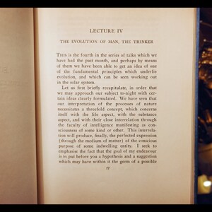 May include: A close-up of a page from a book titled "LECTURE IV THE EVOLUTION OF MAN, THE THINKER". The text discusses the concept of evolution and the interrelation of life, substance, and intelligence.