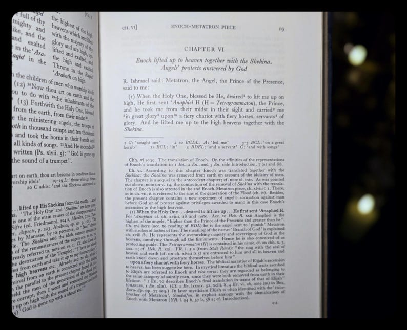 May include: An open book with English text discussing Enoch and Metatron. The right-hand page is fully visible, the left partially. The book has aged pages and a dark background.