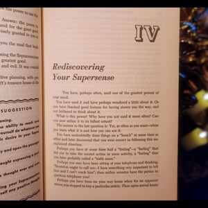 May include: A book titled "Rediscovering Your Supersense" with the Roman numeral IV on the cover. The book is open to a page with the title "Rediscovering Your Supersense" and text about using the power of your mind.
