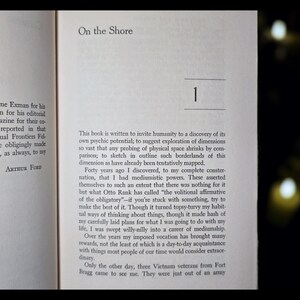 May include: Open book pages with text. The title "On the Shore" is at the top, with the number "1" below it. The text includes the author's name, Arthur Ford, and the beginning of a chapter.