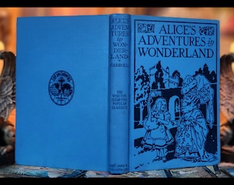 May include: A blue hardcover book with the title "Alice's Adventures in Wonderland" by Lewis Carroll. The book is part of the Winston Clear-Type Popular Classics series.