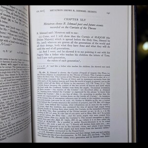 May include: An open book with text on aged paper. The text includes the chapter title "Metatron Shows R. Ishmael Secrets" and the text "Chapter XLV". The pages are yellowed with age.