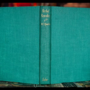 May include: A teal green hardcover book with the title "Herbal Remedies" and the author's name "M.T. Quelch" on the spine. The book is published by Faber.