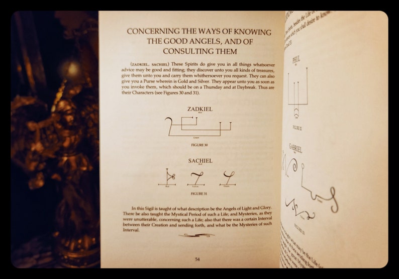 K&ouml;nnte beinhalten: Eine Seite aus einem Buch &uuml;ber Engel, die die Sigillen von Zadkiel und Sachiel zeigt. Der Text beschreibt, wie man diese Engel um Rat und Sch&auml;tze bittet. Die Sigillen sind in schwarzer Tinte auf einer cremefarbenen Seite gezeichnet.