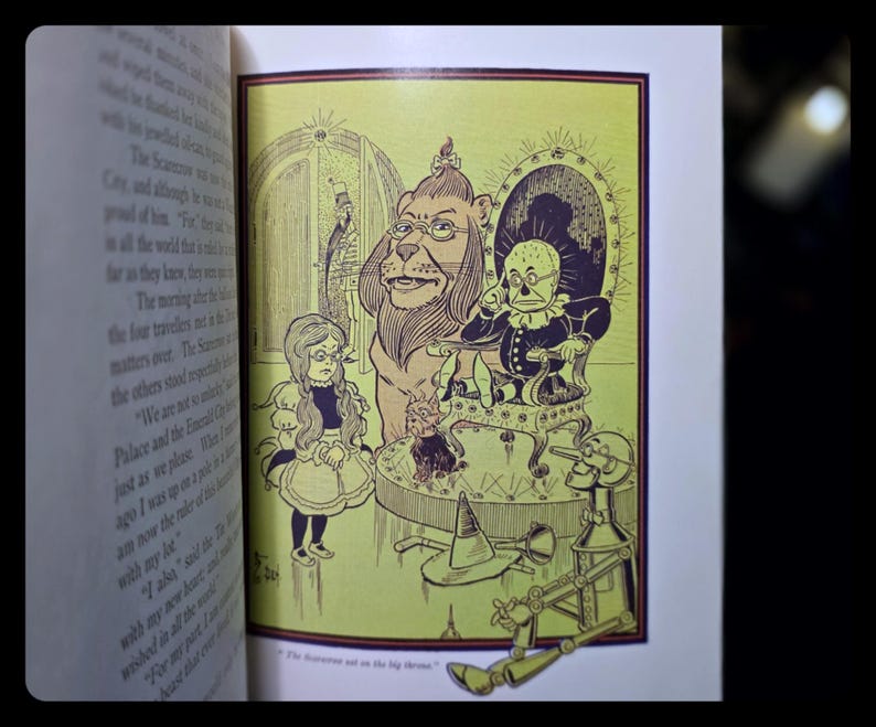 Puede incluir: Ilustraci&oacute;n de un libro con personajes de El Mago de Oz. Dorothy, el Le&oacute;n, el Espantap&aacute;jaros y el Hombre de Hojalata se representan en una escena con el Mago. La imagen est&aacute; en tonos de verde, amarillo y negro.