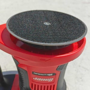 May include: A red and black Bauer 20V Lithium sander. The sander has a round, black sanding pad with a hook and loop surface. The body of the sander is red with black accents and the Bauer logo.