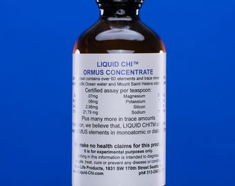 May include: A brown glass bottle with a black cap, labeled "LIQUID CHI™ ORMUS CONCENTRATE." The label lists mineral content per teaspoon, including magnesium, potassium, silicon, and sodium. The bottle is against a blue background.
