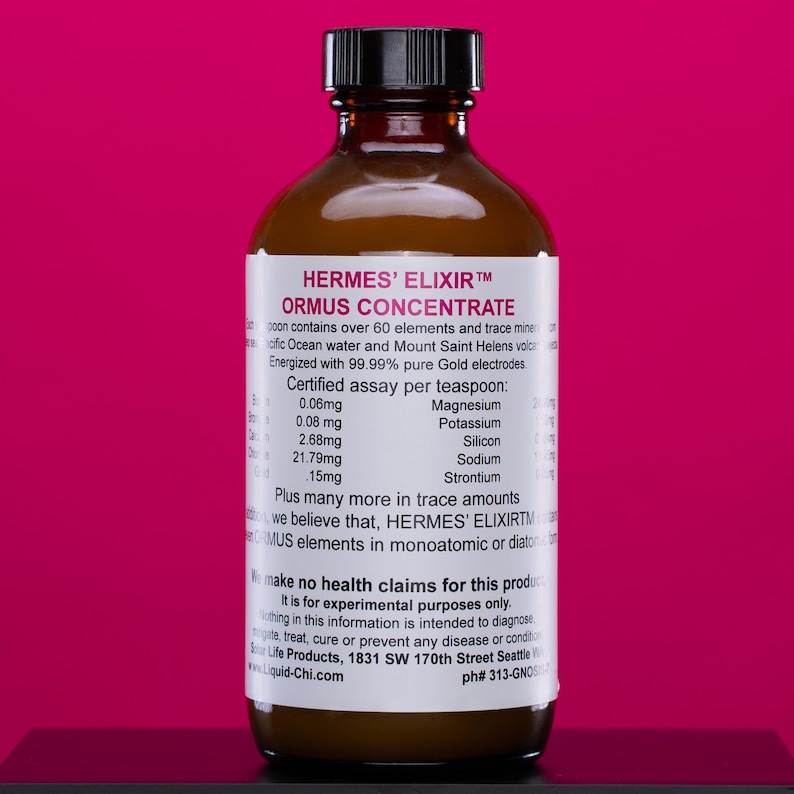 Puede incluir: Una botella de vidrio marr&oacute;n con tapa negra, etiquetada como "HERMES' ELIXIR ORMUS CONCENTRATE". La etiqueta enumera ingredientes y minerales traza. La botella est&aacute; sobre un fondo magenta.