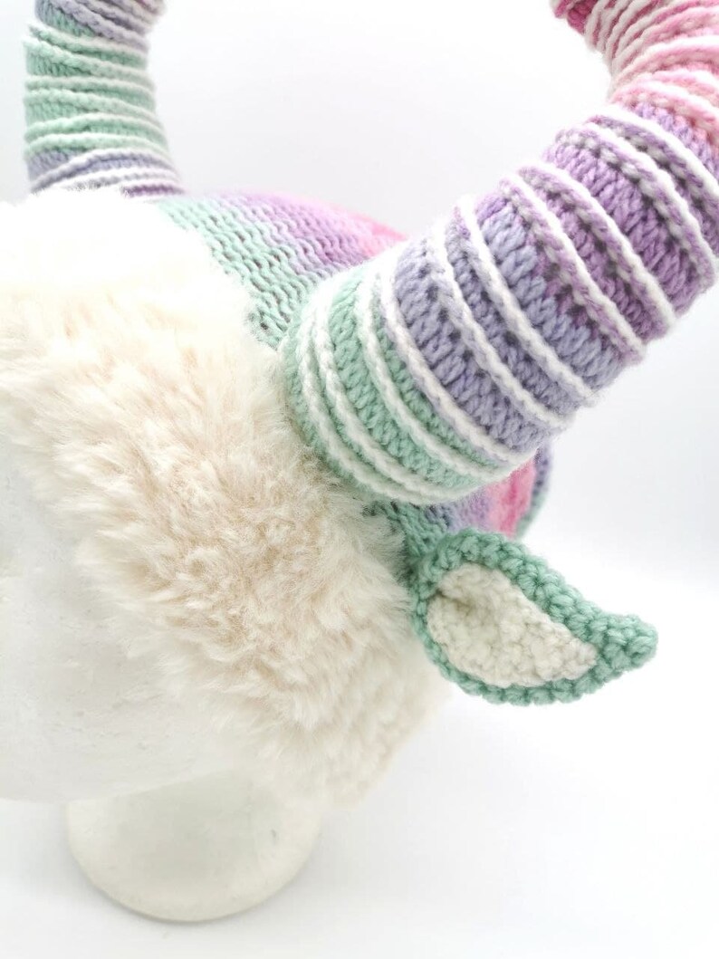 May include: A whimsical, handmade unicorn horn headband. The horns are striped with pastel colors, including pink, purple, and green. The base is covered in soft, cream-colored faux fur, with matching ears. A unique accessory for costume or everyday wear.
