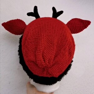 Puede incluir: Un sombrero rojo de ganchillo con ribete de piel sint&eacute;tica negra, cuernos negros y orejas rojas. Este sombrero hecho a mano es un accesorio &uacute;nico para fiestas de disfraces o eventos tem&aacute;ticos.