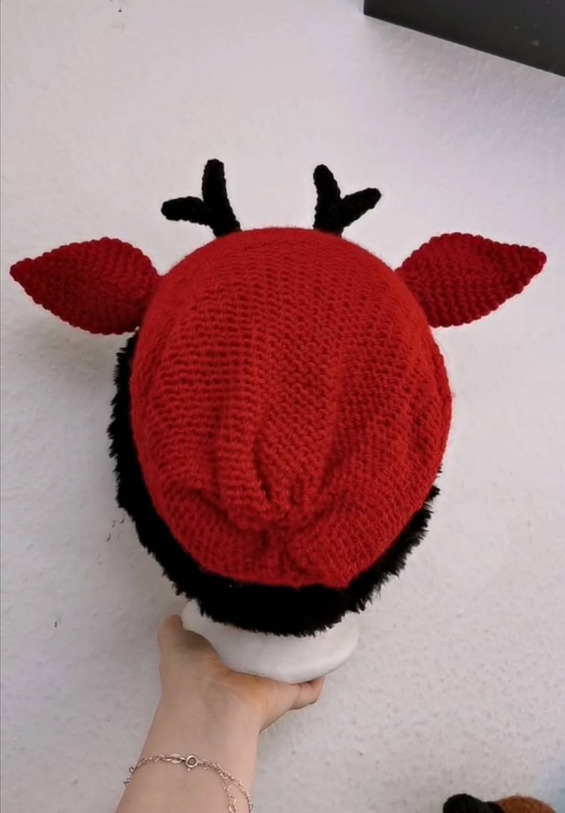 Puede incluir: Un sombrero rojo de ganchillo con ribete de piel sint&eacute;tica negra, cuernos negros y orejas rojas. Este sombrero hecho a mano es un accesorio &uacute;nico para fiestas de disfraces o eventos tem&aacute;ticos.