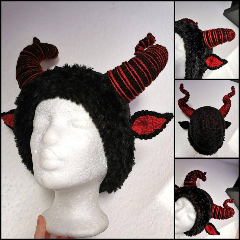 K&ouml;nnte beinhalten: Ein schwarzes und rotes geh&ouml;rntes Kopfst&uuml;ck mit pelziger Textur. Die H&ouml;rner sind mit rotem und schwarzem Garn gestreift. Die Ohren sind rot mit schwarzem Rand. Das Kopfst&uuml;ck wird auf einem wei&szlig;en Schaufensterpuppenkopf pr&auml;sentiert.