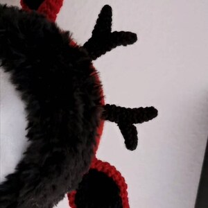 Puede incluir: Una diadema de cuernos de ganchillo negros y rojos. Los cuernos son negros con ribetes rojos, y la diadema est&aacute; cubierta de piel sint&eacute;tica negra. El dise&ntilde;o es un accesorio festivo, adecuado para eventos tem&aacute;ticos o disfraces.