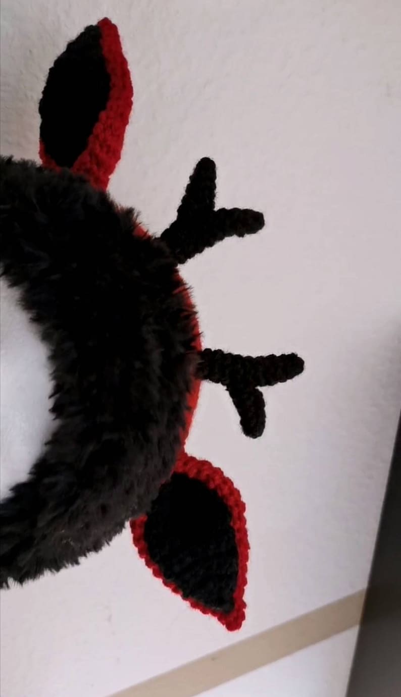 Puede incluir: Una diadema de cuernos de ganchillo negros y rojos. Los cuernos son negros con ribetes rojos, y la diadema est&aacute; cubierta de piel sint&eacute;tica negra. El dise&ntilde;o es un accesorio festivo, adecuado para eventos tem&aacute;ticos o disfraces.