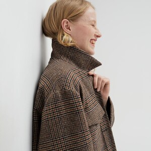 Brown, dark brown and beige checkered fall winter warm shirt jacket with warm lining, long sleeves and pockets.