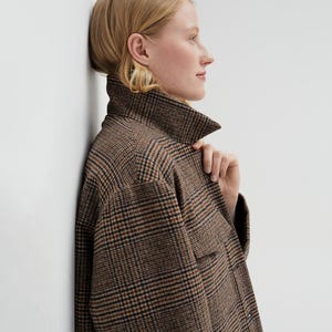Brown, dark brown and beige checkered fall winter warm shirt jacket with warm lining, long sleeves and pockets.